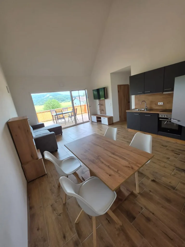 Wohnraum mit Esstisch, dunkle Küche und Couch