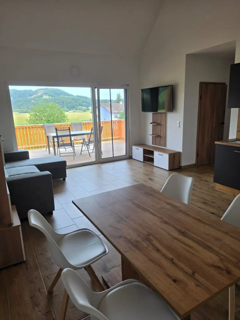Wohnraum mit Esstisch aus Holz und Couch mit Fernseher